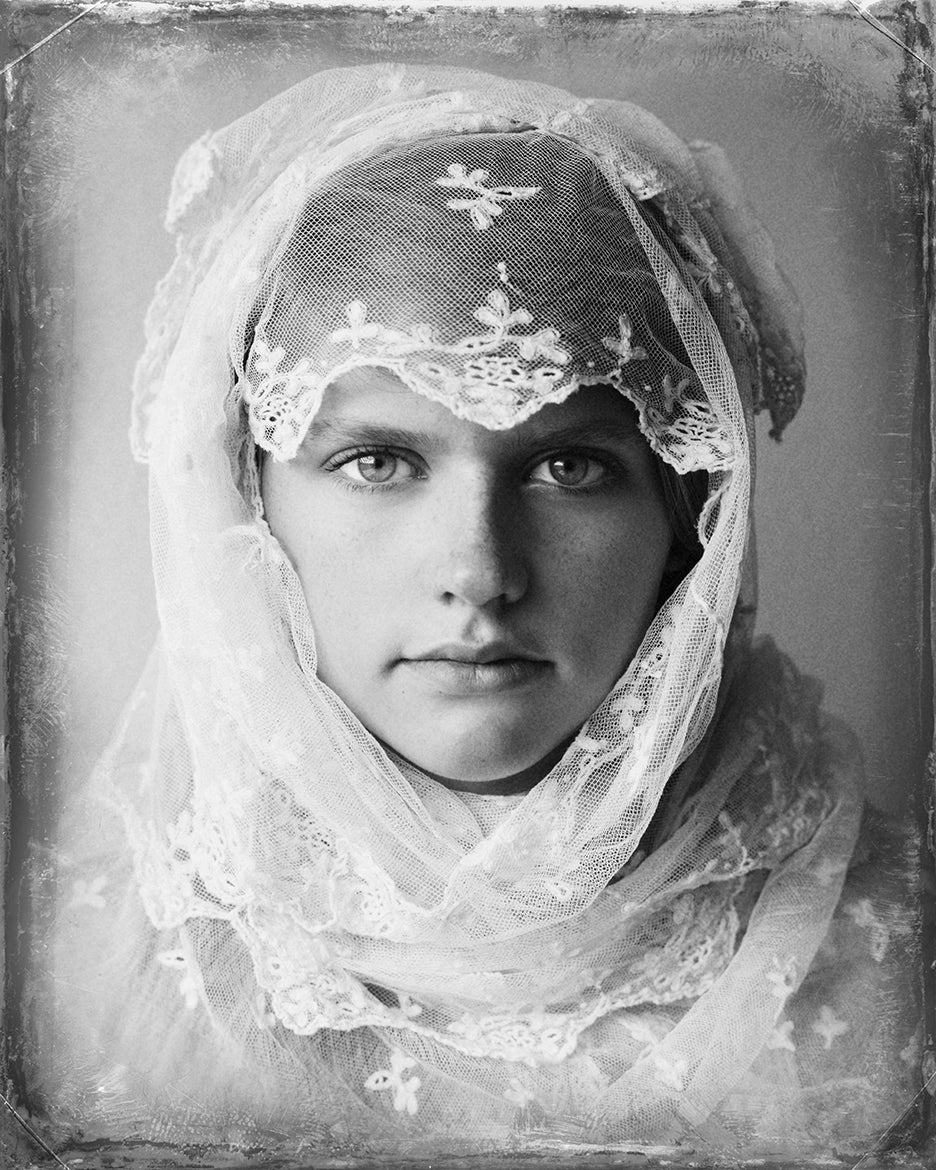A fine art black and white photograph featuring a girl with English lace draped over her head.