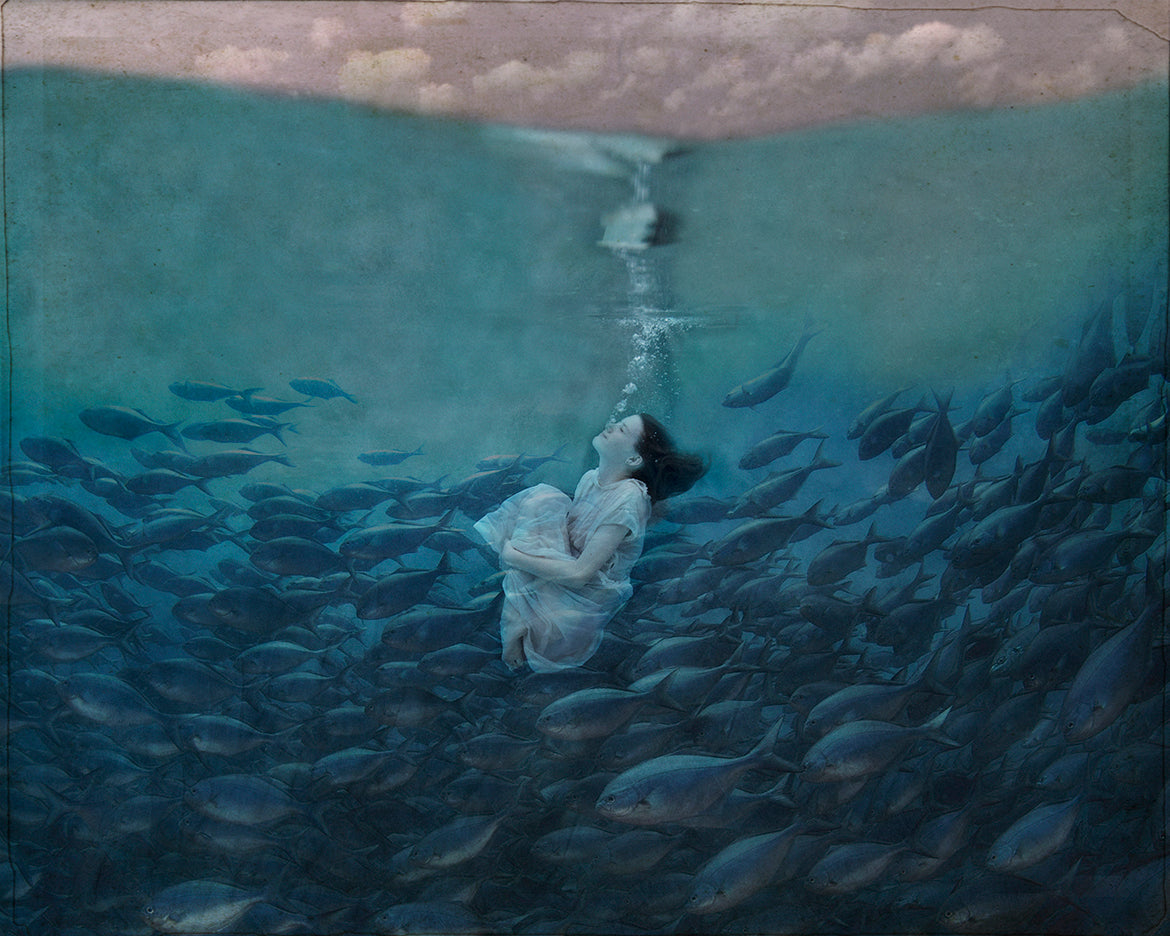 A photograph of a girl underwater surrounded by fish, with a whimsical, ethereal artistic style.