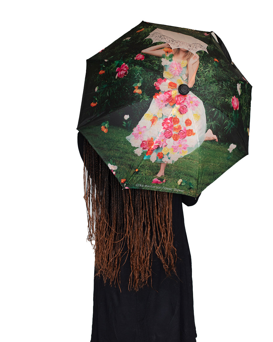 A person holding an umbrella with a floral pattern featuring a girl showered with flowers.
