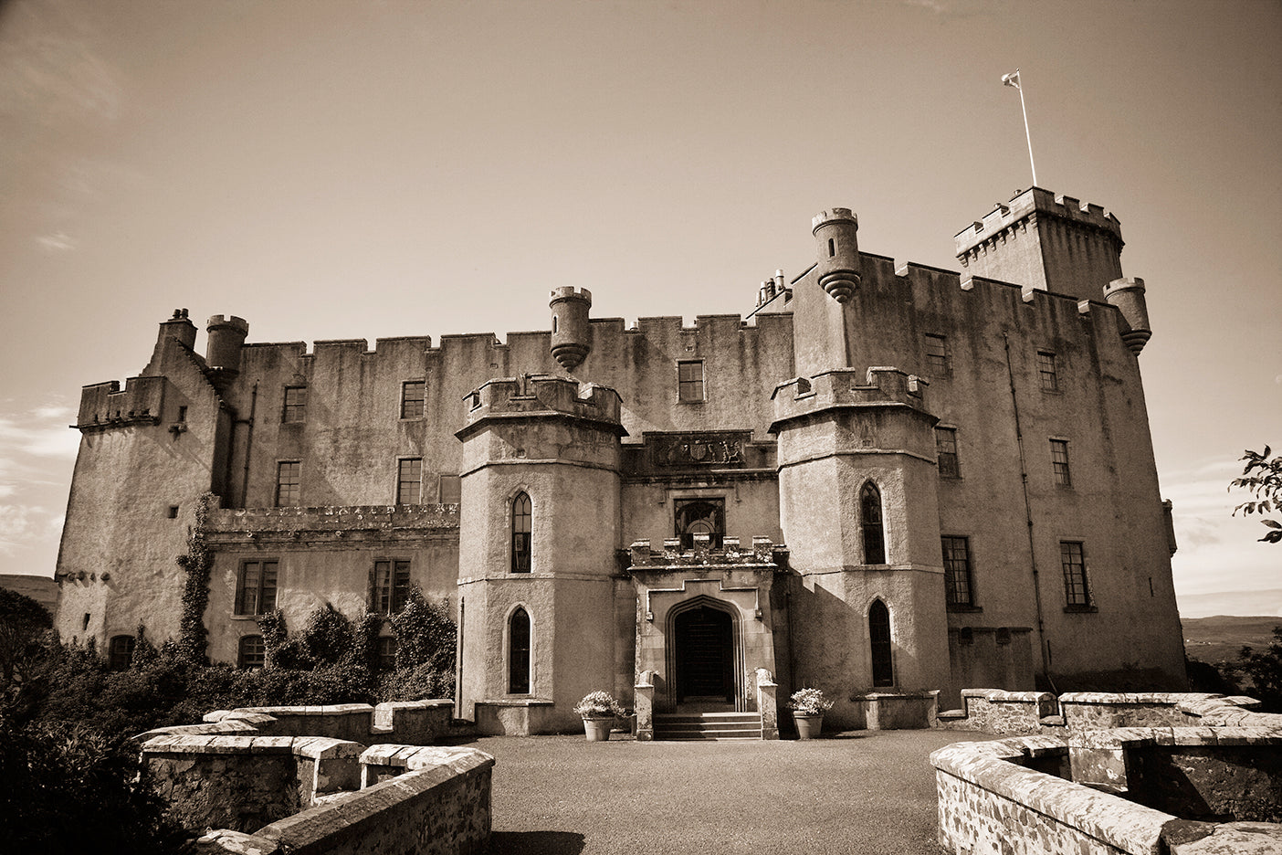 Black and white photograph of Dunvegan Castle, a historic castle in Scotland with a rugged and old-world appearance.