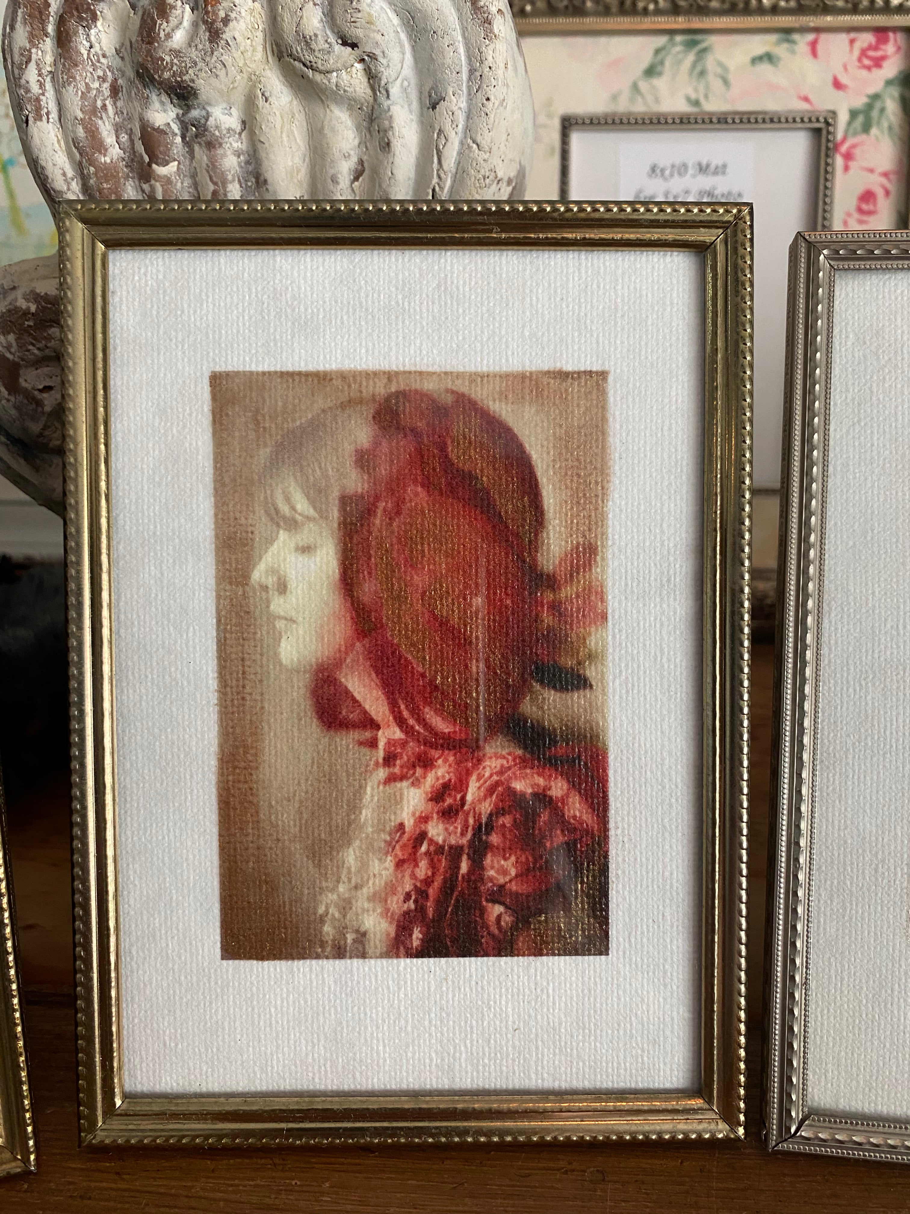 A vintage gold frame mini hand-painted artwork featuring a red-headed woman with a floral crown on a white background, displayed in a store among other framed art pieces.