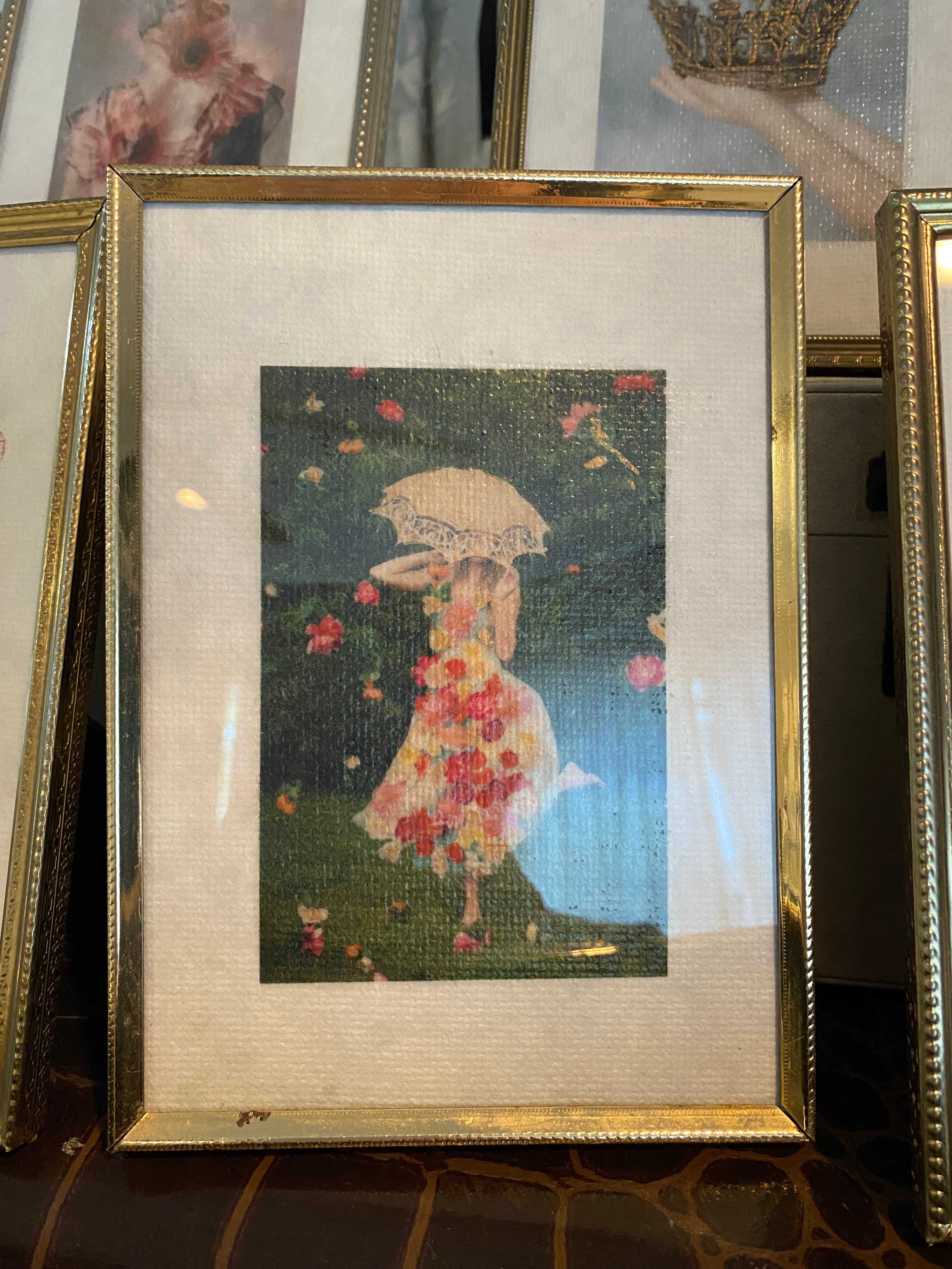 A vintage gold frame containing a hand-painted mini artwork depicting a floral theme with gold ink on mulberry paper.