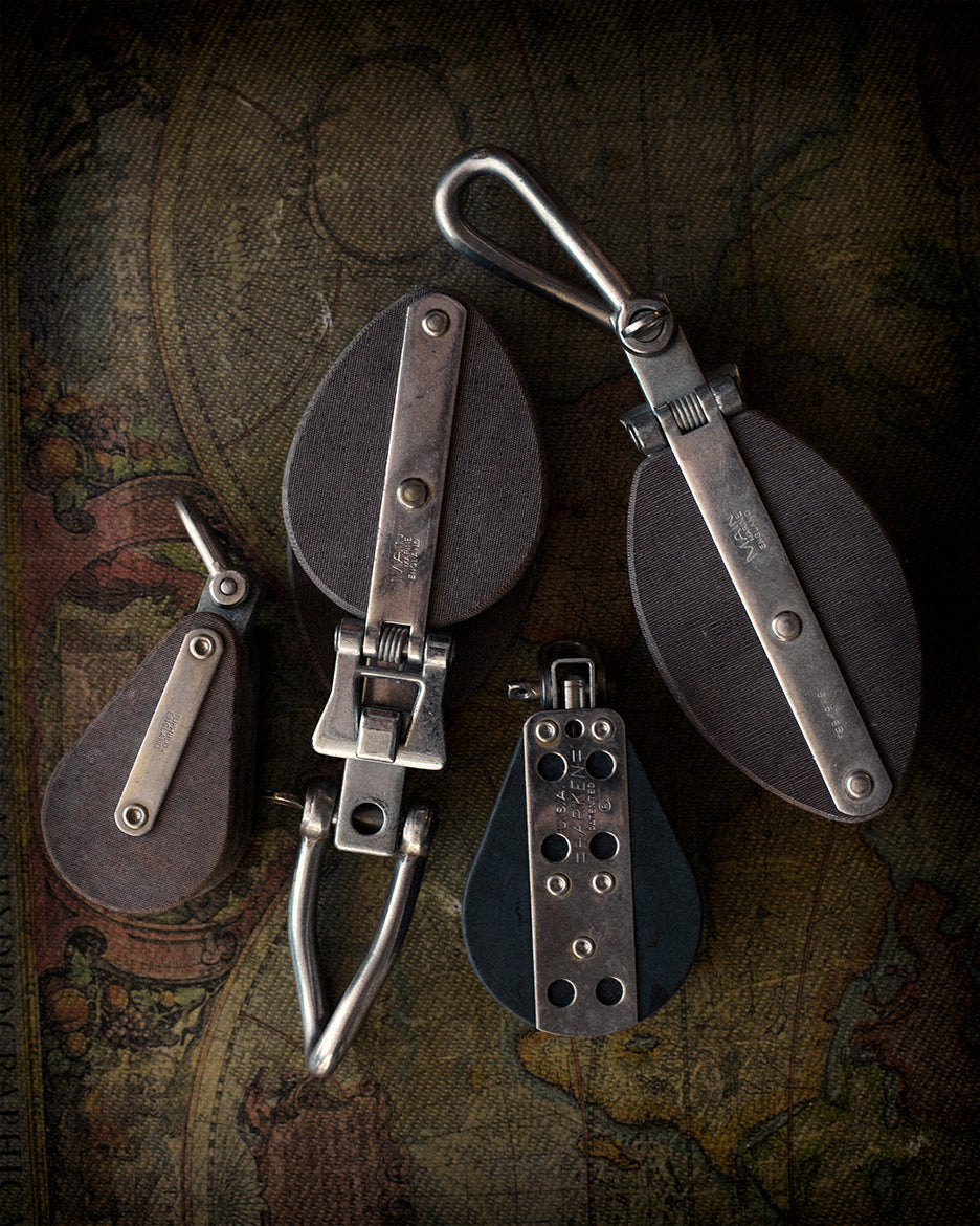 A collection of four different sized metal pulleys arranged on a map background, with a vintage and monochrome aesthetic.