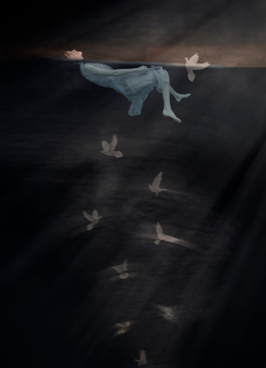 A fine art photograph featuring a girl submerged underwater with doves flying around her, symbolizing peace and renewal.