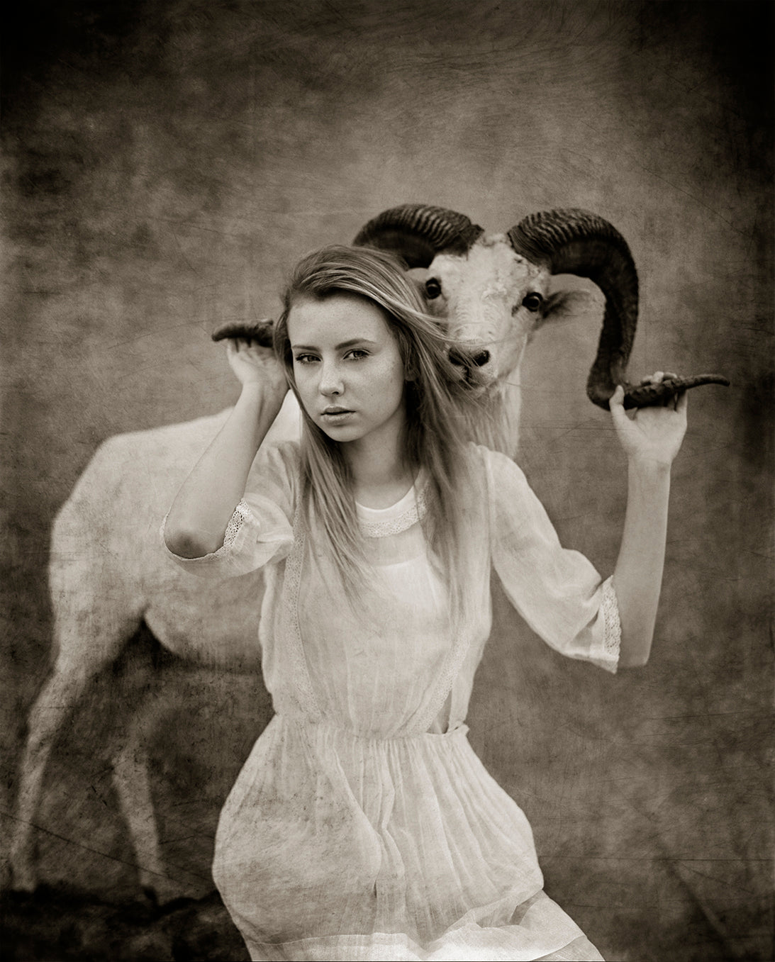 girl holding the antlers of a wild ram