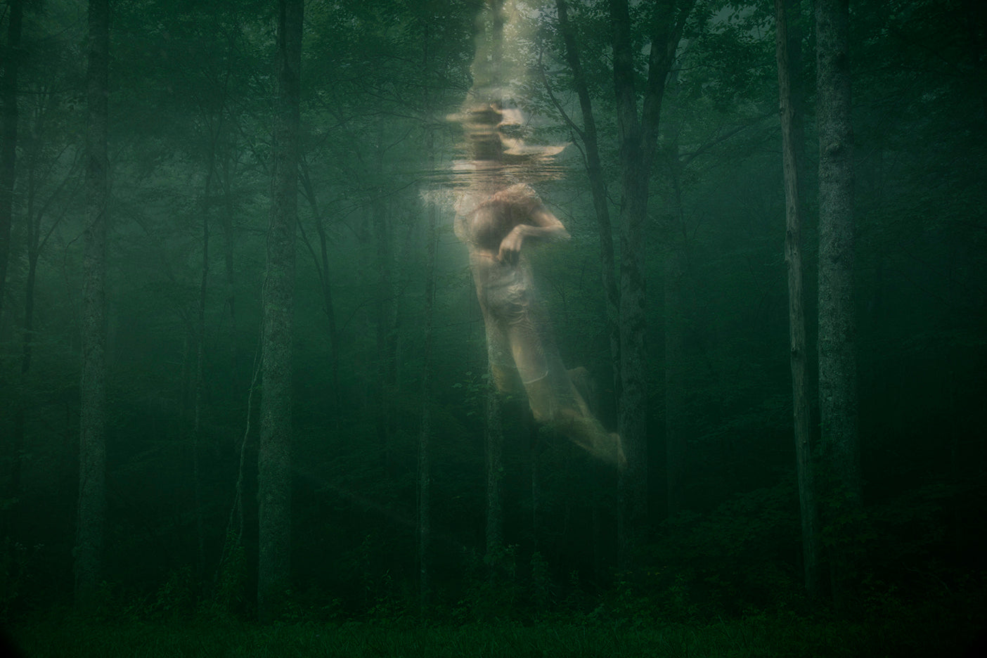 An ethereal image featuring a figure underwater, surrounded by a serene forest-like environment with trees and a misty atmosphere.