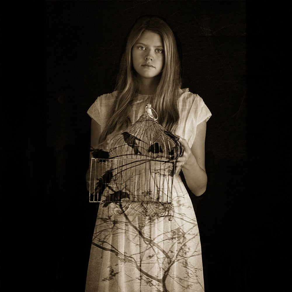 A black and white photograph of a woman holding a birdcage, with a sepia tone and a dressy outfit.