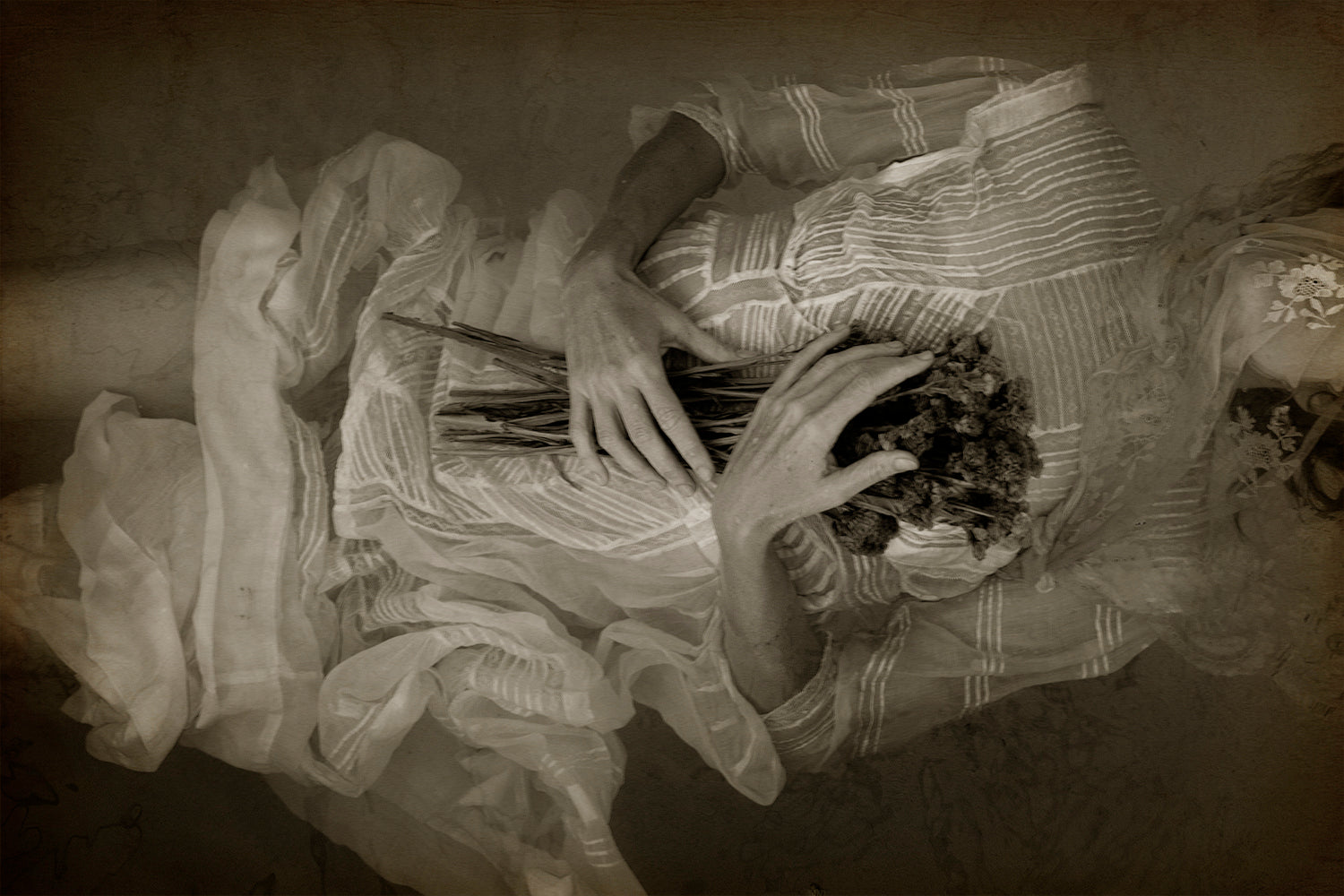 A black and white photograph of a person's hands holding flowers with a soft focus on the hands and a blurred background.