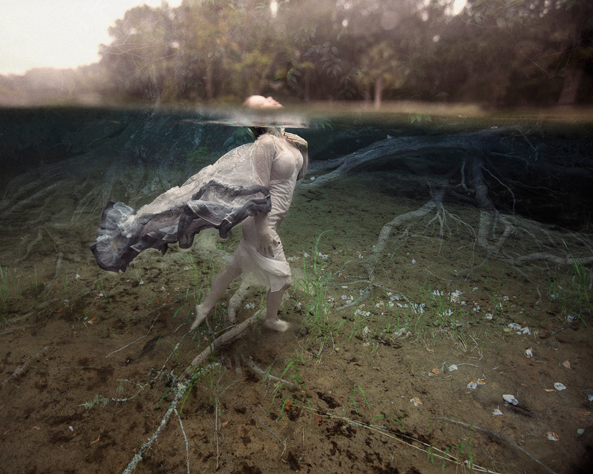 A fine art photograph featuring a girl underwater, walking across the sandy bottom, with a serene and ethereal atmosphere.