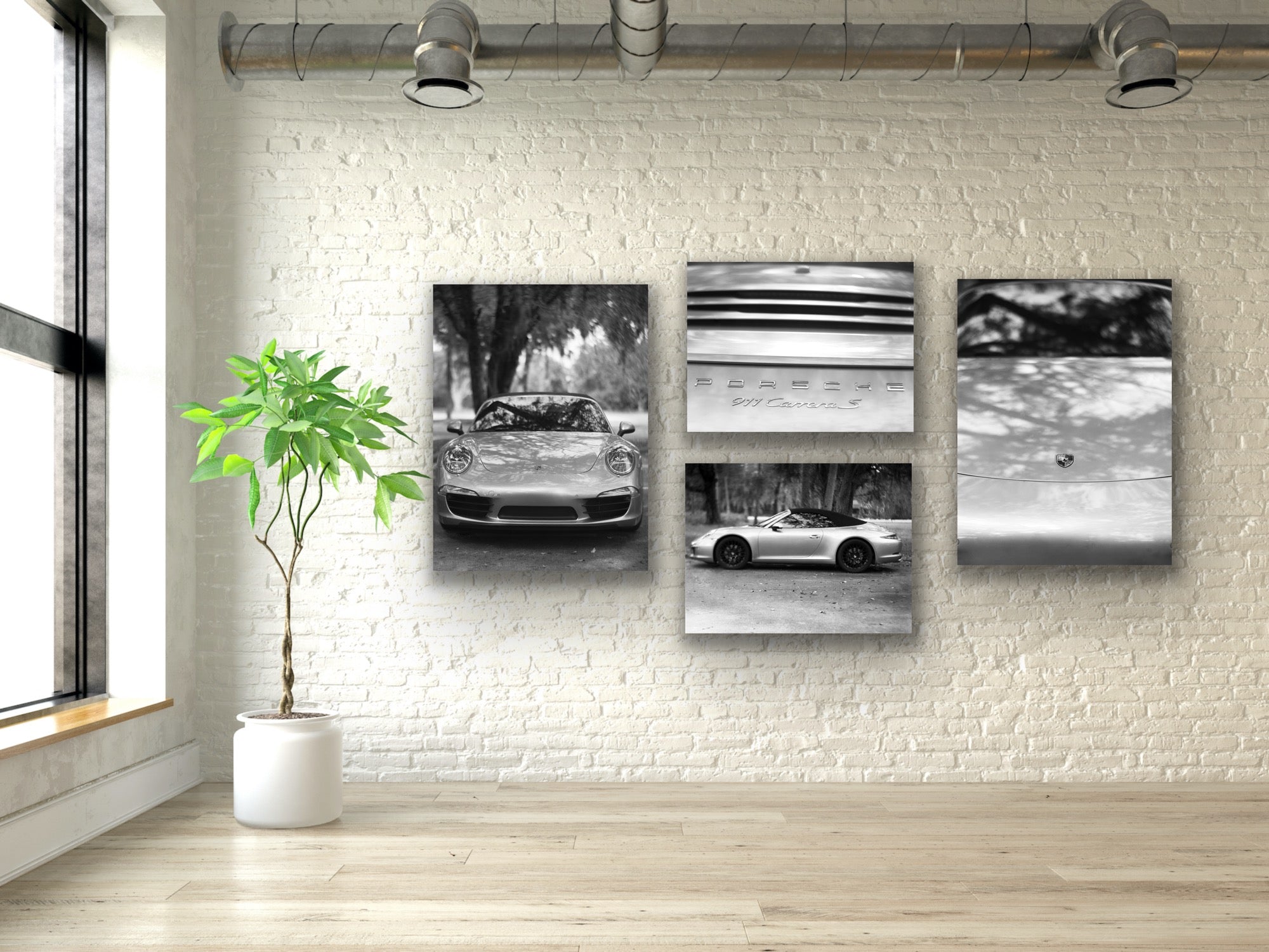 Four black and white car photographs on a white brick wall with a plant and window.