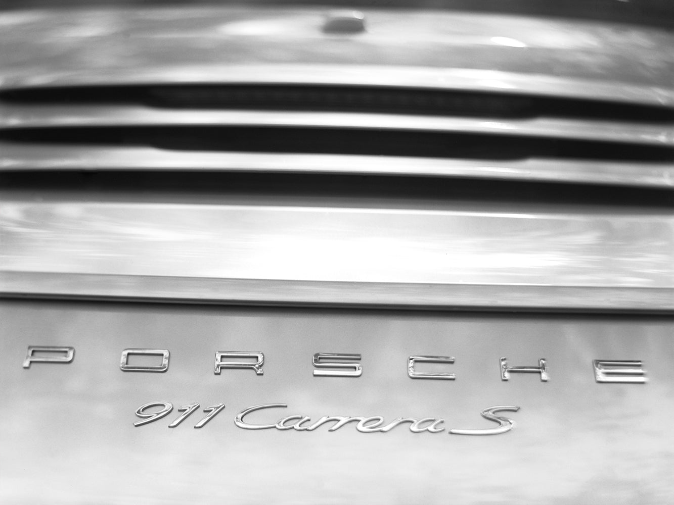 Close-up of a Porsche 911 Carrera S badge on a metallic surface