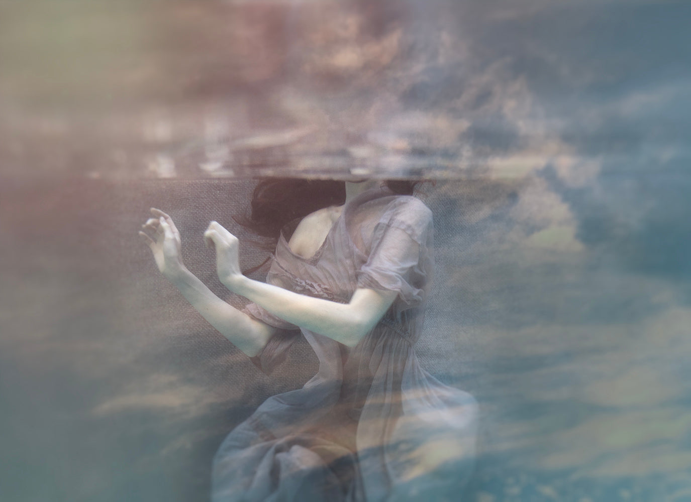 A double exposure image featuring a figure in a dress overlaying a background of underwater scene with clouds and light rays.