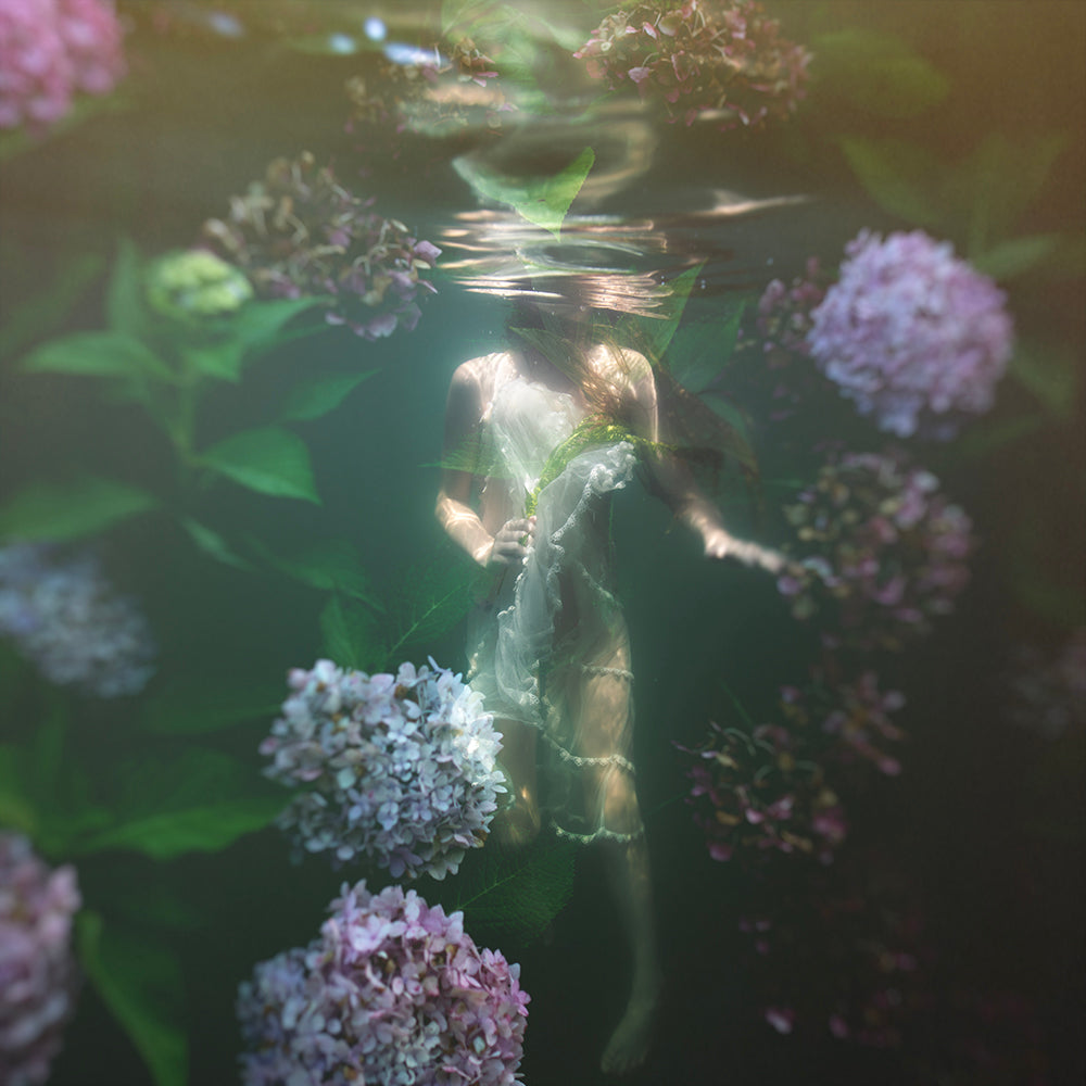 Ethereal underwater photograph featuring a figure with floral elements, capturing a whimsical and magical aesthetic.